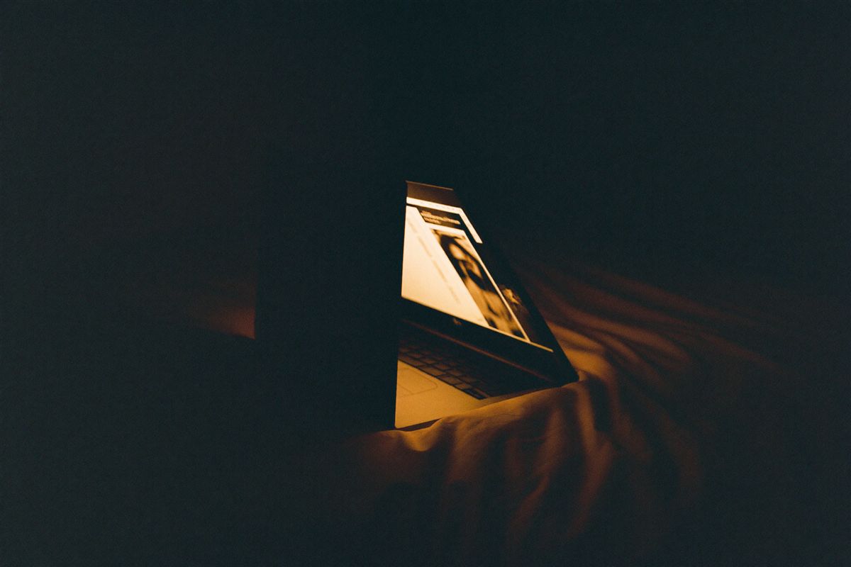 Laptop glowing in a dark room at night